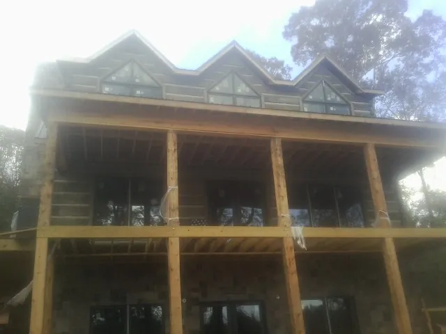 Dormers and porch framing on a large log home under construction — Roof Coating work by our crew in Furman