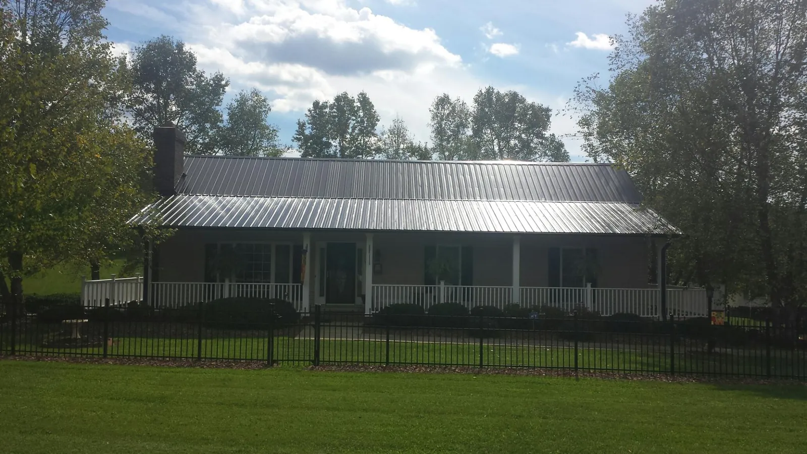 Gray metal roof on a brick ranch with a full width front porch — Gutter Guard Installation work by our crew in Furman